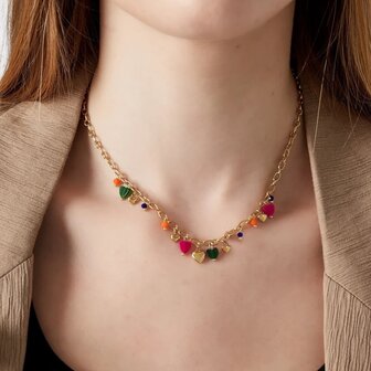 Persoon draagt gouden ketting met gekleurde hartjes bedels detail