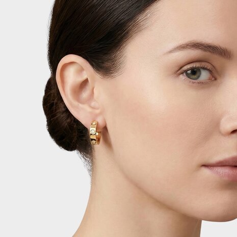 Persoon draagt kleine gouden creool oorbellen met witte zirconia steentjes